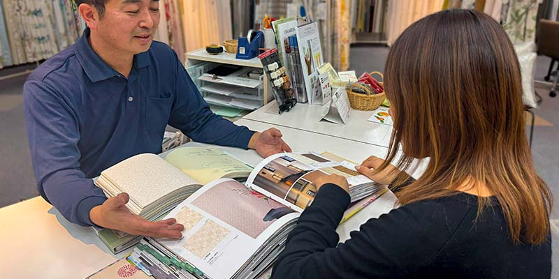 お客様にカーテンの説明をするリノプラススタッフ
